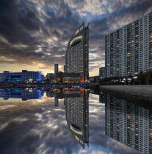 un reflet des bâtiments dans une masse d'eau dans l'établissement Bayshore Hotel Dalian, à Dalian