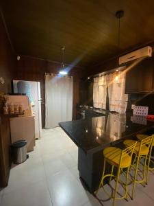 una cocina con encimera y taburetes amarillos. en Casa Rio da Madre, en Palhoça