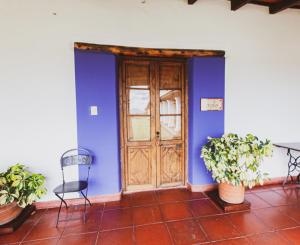 a blue wall with a wooden door and two chairs at Finca Las Margaritas in Chicoana