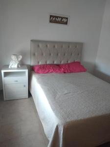 1 cama con almohada roja y mesita de noche en Olivia Apart frente plaza centro con cochera en Villa María