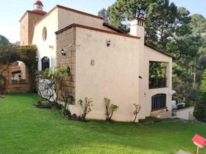 une maison avec une pelouse verte devant elle dans l'établissement Alojamiento Cúpulas Avandaro, à Valle de Bravo
