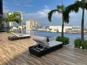 una terrazza con 2 sedie a sdraio e palme in un edificio di Cozy 1-7 pax Sunway Pyramid 2Room Wifi TV Balcony a Petaling Jaya