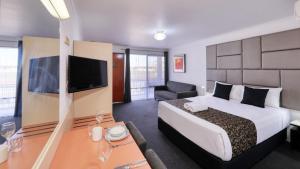 Habitación de hotel con cama grande y TV en City Reach Motel, en Wangaratta