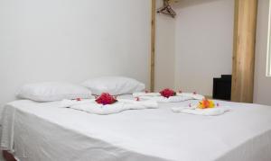 a white bed with four pillows and flowers on it at Apartamentos Palo Coco in Las Terrenas