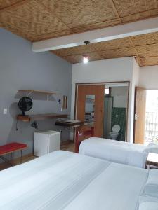a bedroom with two white beds and a table at Pousada Santa Maria in Tiradentes