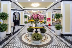 een lobby met een tafel met bloemen en planten bij HƯỚNG DƯƠNG HOTEL THANH HOÁ in Thanh Hóa