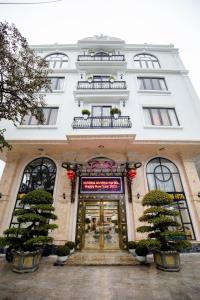 un grande edificio bianco con una porta d'oro e due alberi di HƯỚNG DƯƠNG HOTEL THANH HOÁ a Thanh Hóa