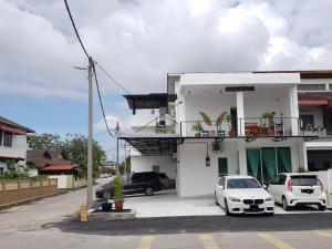 a white building with cars parked in a parking lot at casa 96 villa in Kuantan