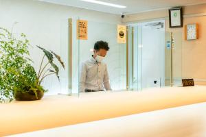 a man wearing a face mask in a room at Kumamoto Ichibamae Business Kurenai Hotel in Kumamoto