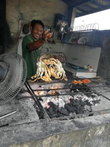 a man is cooking food on a grill at Lavanda guesthouse/homestay in Jimbaran