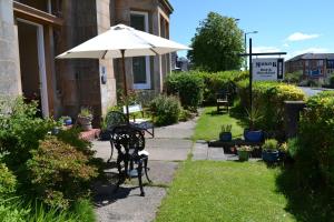 a patio with a table and an umbrella at Maybank Guest House in Helensburgh