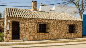 un edificio de piedra con 3 ventanas en una calle en El Rincón de Burujón, en Burujón