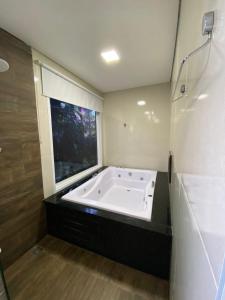 uma grande banheira na casa de banho com uma janela em Trakai Suites em Ubatuba