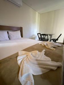 a bedroom with a bed with white sheets on it at Trakai Suites in Ubatuba