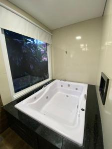 a white bath tub in a bathroom with a window at Trakai Suites in Ubatuba
