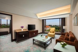 ein Wohnzimmer mit einem Sofa und einem TV in der Unterkunft Xiamen C&D Hotel-Free Welcome Snacks-Oasis Garden in Xiamen