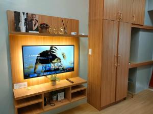 uma sala de estar com uma televisão de ecrã plano num centro de entretenimento em madeira em Tagaytay Wind Residences em Tagaytay