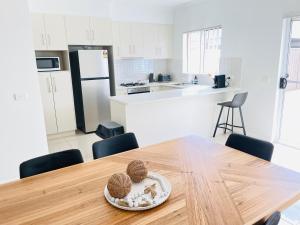 uma cozinha com uma mesa de madeira com cadeiras e um frigorífico em Modern City Townhouse with all the Comforts em Wagga Wagga