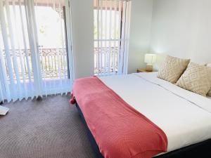 um quarto com uma cama grande e 2 janelas grandes em Modern City Townhouse with all the Comforts em Wagga Wagga