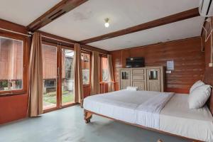 ein Schlafzimmer mit einem großen Bett und einigen Fenstern in der Unterkunft Kanaka Residence Mitra RedDoorz in Bandungan