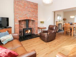 a living room with a brick fireplace and leather furniture at Lightkeeper House in Amble