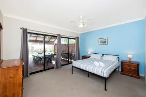 a bedroom with blue walls and a bed and a table at Holiday on the Terrace in Dunsborough