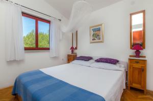 a white bedroom with a bed and a window at Apartments Ana in Blato