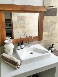 lavabo blanco en el baño con espejo en Amel House, en Gili Air