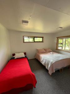 a bedroom with two beds and a red blanket at Turismo y cabañas Chulengo in Cochrane