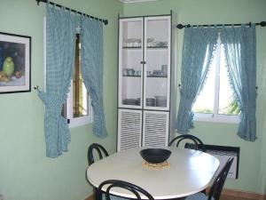 a table and chairs in a dining room with blue curtains at House - 2 Bedrooms with WiFi - 00117 in Bueu