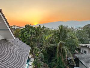 a view of a sunset from a house with a palm tree at Comfy Boutique House in Chiang Mai