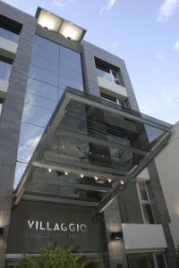 un edificio di vetro alto con un cartello sopra di Villaggio Hotel Boutique a Mendoza