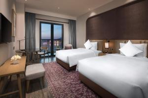 una camera d'albergo con due letti e un tavolo con sedie di Crowne Plaza QingdaoOrientalMovieMetropolis, an IHG Hotel a Huangdao