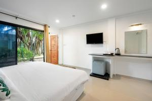 a white bedroom with a bed and a tv at 4U Resort Samui in Lamai