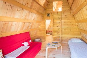 a room with a red couch in a wooden cabin at Ferme Rony Camp des Découvreurs in Saint-Nizier-du-Moucherotte