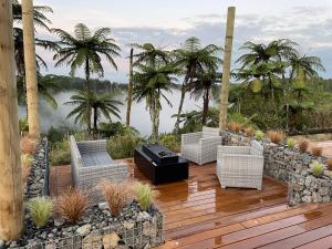 a deck with chairs and a grill on top of a house at Pukeko Lane in Tauranga