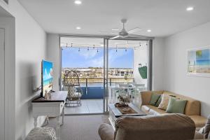 a living room with a couch and a large window at Pool, 100m to Hosp, 3 TVs, 3 Beds - Lakefront Aquarius Apartment in Kawana Waters