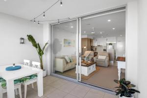 een woonkamer met een tafel en een woonkamer bij Pool, 100m to Hosp, 3 TVs, 3 Beds - Lakefront Aquarius Apartment in Kawana Waters
