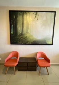 deux chaises et une peinture accrochée au mur dans l'établissement Kensington Sunrise at Sg Palas,PalasHorizon, à Tanah Rata