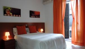 a bedroom with a bed with orange curtains and a window at Hostal Cervantes in Madrid