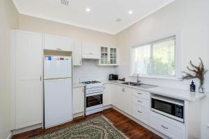 a white kitchen with a refrigerator and a sink at Busselton River Cottage with WiFi in Busselton