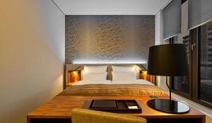 a bedroom with a bed and a table with a lamp at COSMO Hotel Berlin Mitte in Berlin