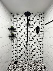 une douche avec un mur carrelé noir et blanc dans l'établissement BELLA COTTAGE, à Pantai Cenang 4 autres photos