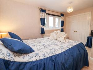 ボートン・オン・ザ・ウォーターにあるRosemary Cottageのベッドルーム(青い枕の大型ベッド1台付)