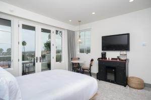a white bedroom with a bed and a flat screen tv at North Beach Villa in San Clemente