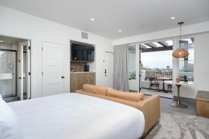a white bedroom with a large bed and a balcony at North Beach Villa in San Clemente