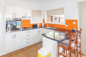 a kitchen with white cabinets and a glass counter top at Cillanti in Sussex inlet +5 photos