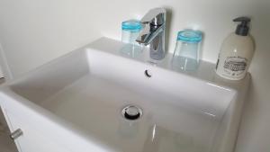 a white sink with two glasses and a bottle on it at vakantiewoning onZENhof in Heuvelland +9 photos