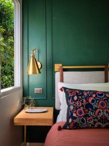 プエルト・プリンセサにあるSwansea Hills Tiny Homeの緑のベッドルーム(ベッド1台、ランプ付きテーブル付)