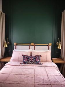 a bedroom with a pink bed with two pillows at Swansea Hills Tiny Home in Puerto Princesa City